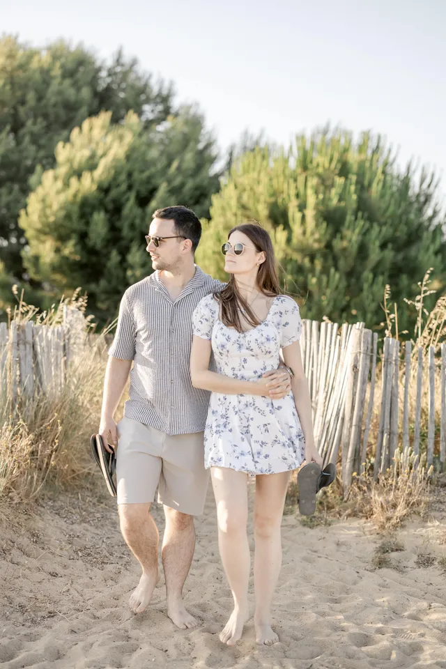 Danni et Connor marchent dans les dunes, sandales à la main, séance couple Hyères