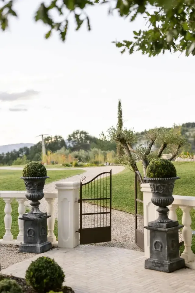 Portail en fer forgé et vasques en pierre à l'entrée du Mas des 5 Fontaines