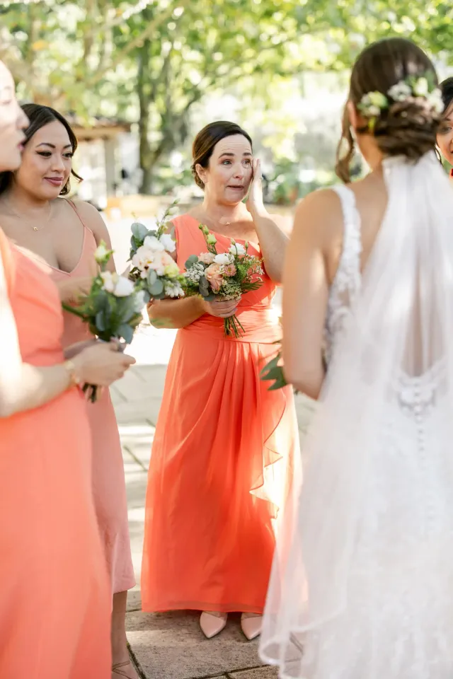 Les demoiselles d'honneur en robes corail avec leurs bouquets