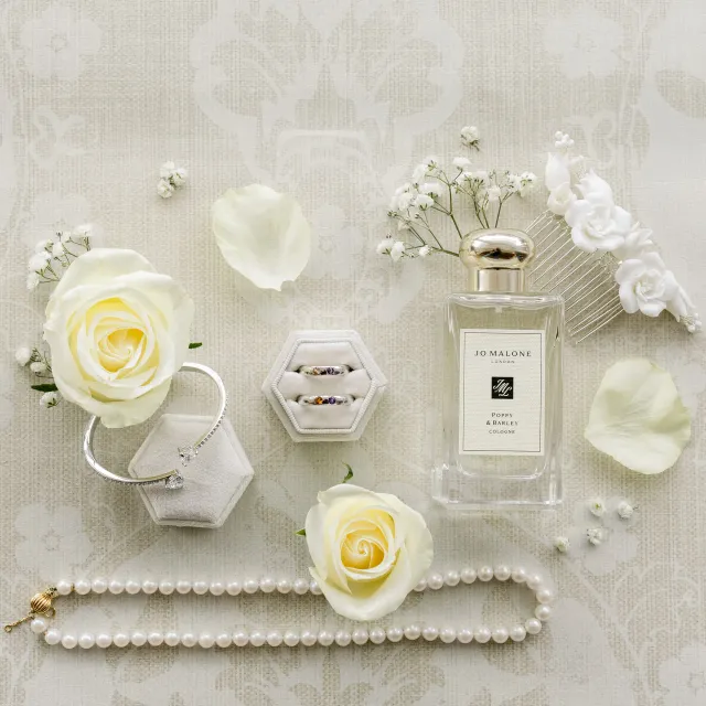 Détails de la mariée : parfum, boucles d'oreilles et roses blanches