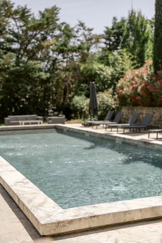 Piscine du domaine bordée de pierre et de transats