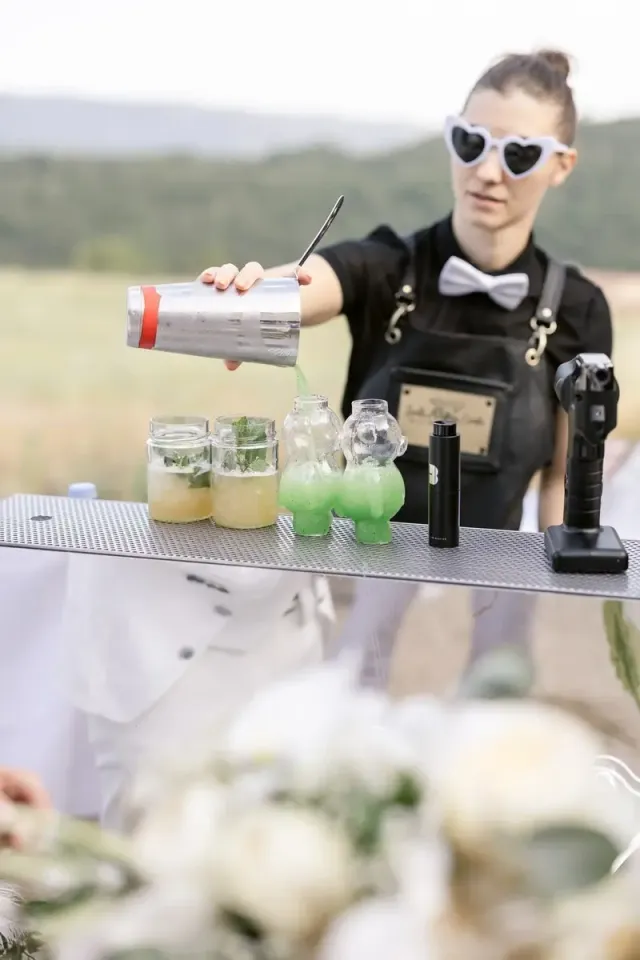 Barmaid versant des cocktails verts devant les collines, bar à cocktails de mariage