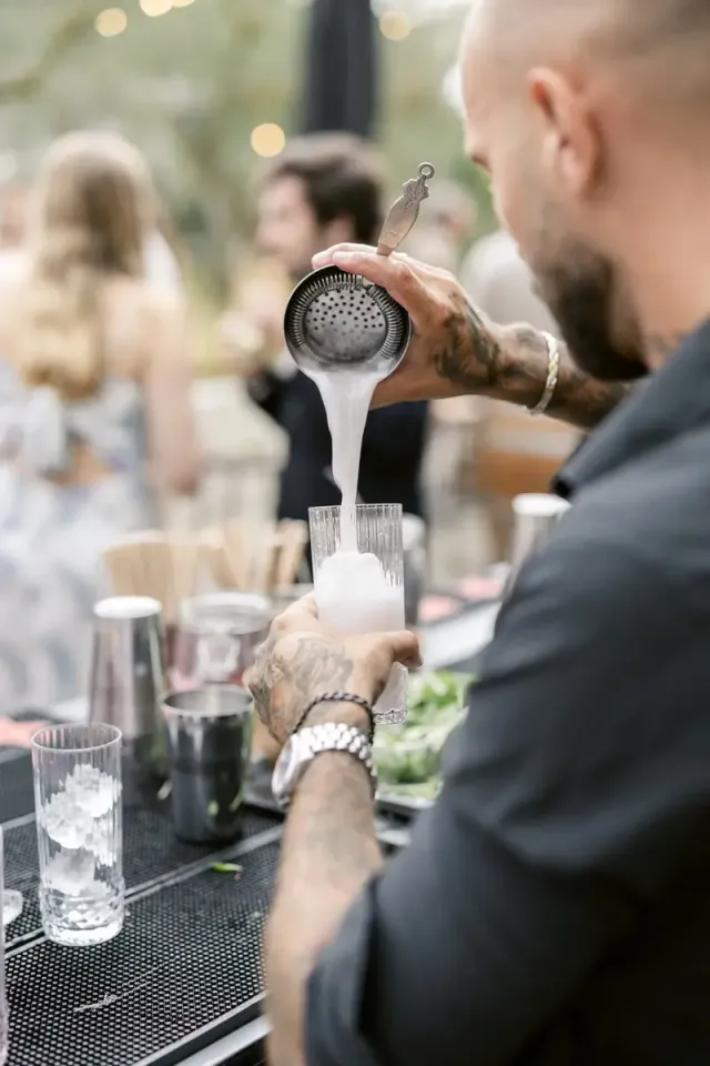 Mixologue préparant un cocktail signature au shaker pendant le cocktail d'un mariage en Provence
