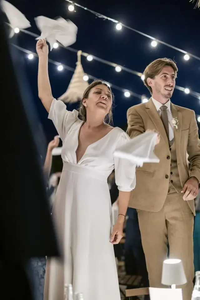 Mariés faisant tourner leur serviette sous les guirlandes lumineuses, soirée festive d'un mariage intime