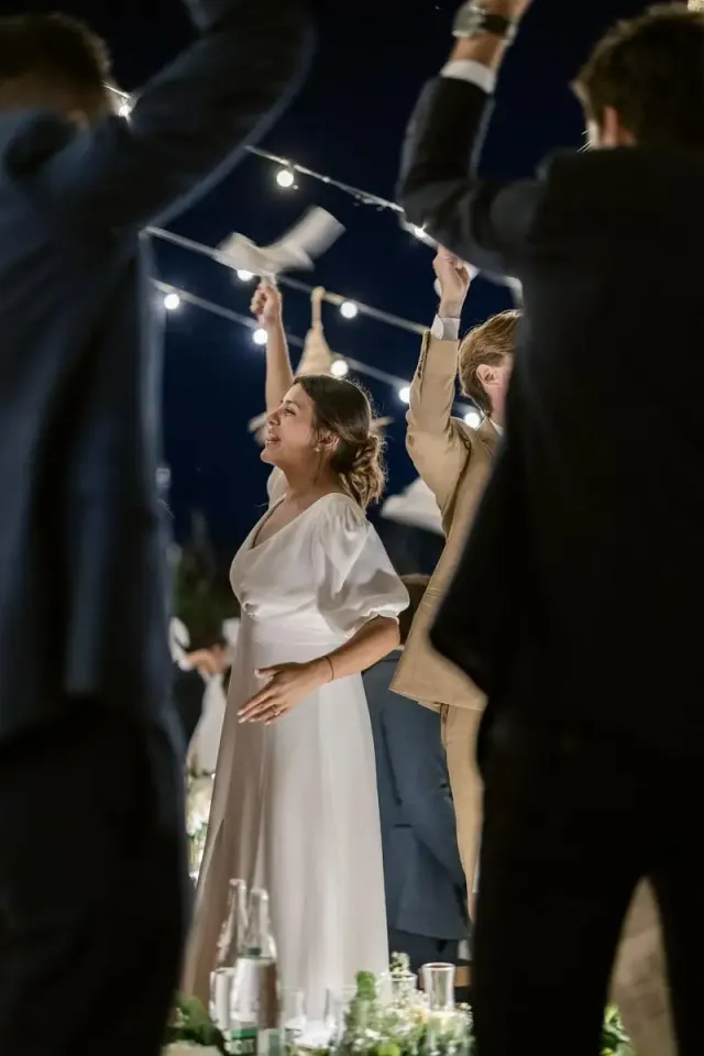 Mariée riant au milieu des invités qui dansent sous les guirlandes guinguette