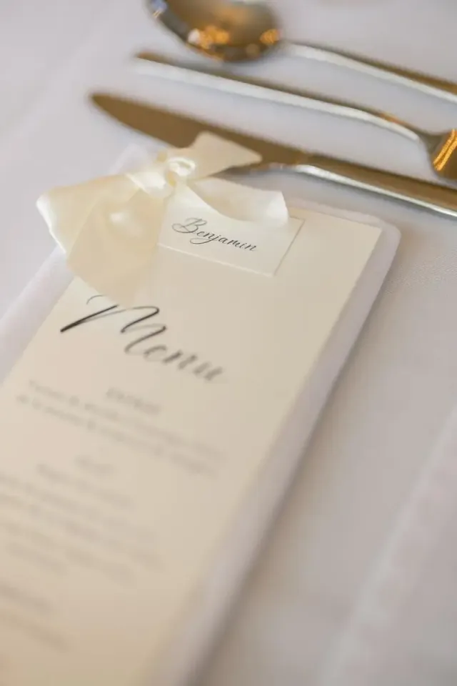 Menu de mariage calligraphié posé sur l'assiette, détail de table sobre et élégant