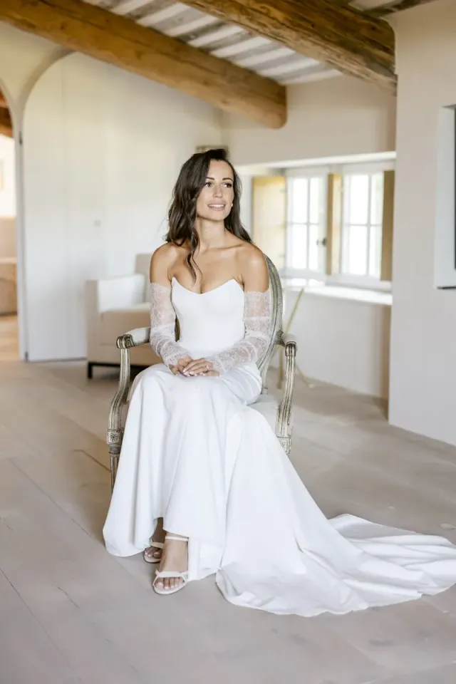 Cécile assise dans le mas de Vacqueyras le jour de son mariage, robe bustier et gants de dentelle
