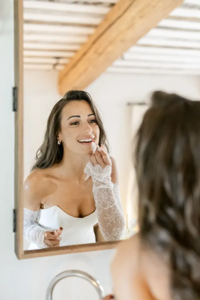 Cécile riant devant le miroir pendant les préparatifs dans le mas