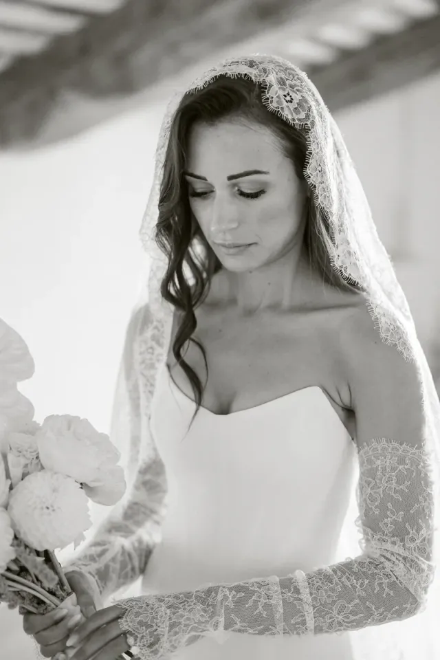 Mariée en noir et blanc, voile de dentelle et gants longs, moment calme avant la cérémonie dans un mas de Provence